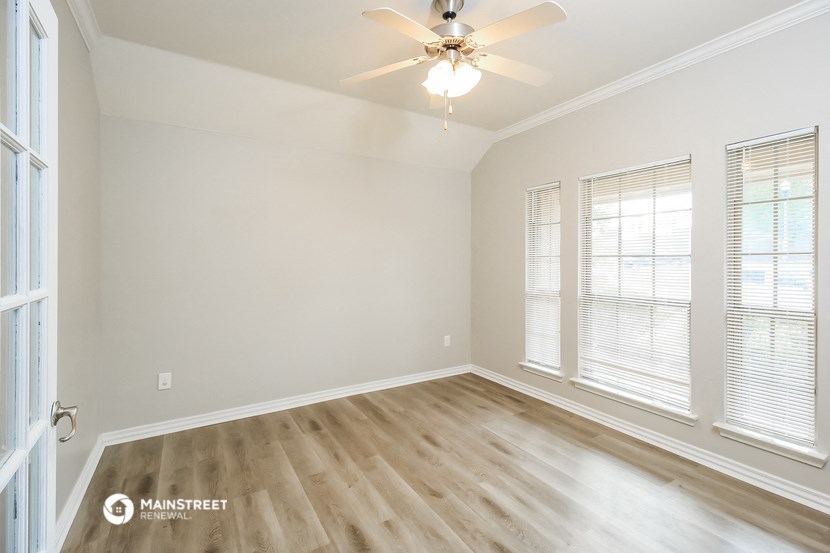 the spacious living room with hardwood floors and a ceiling fan