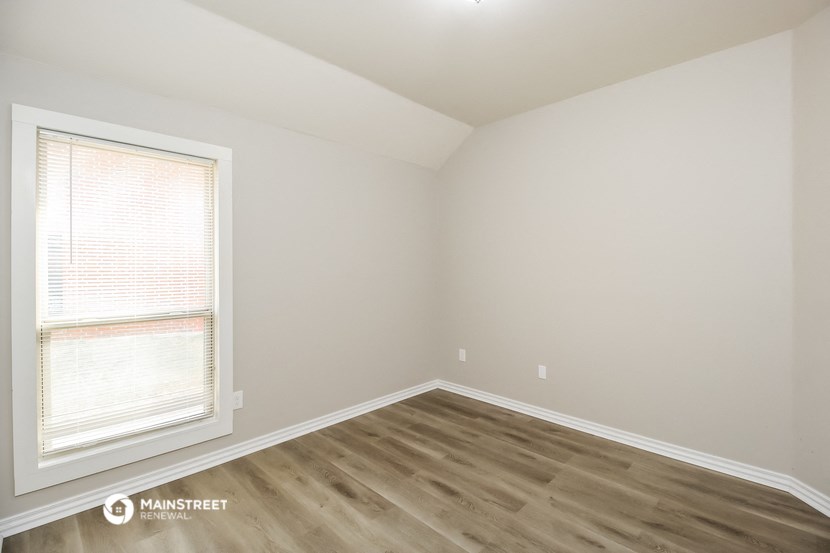 a bedroom with wood flooring and a window
