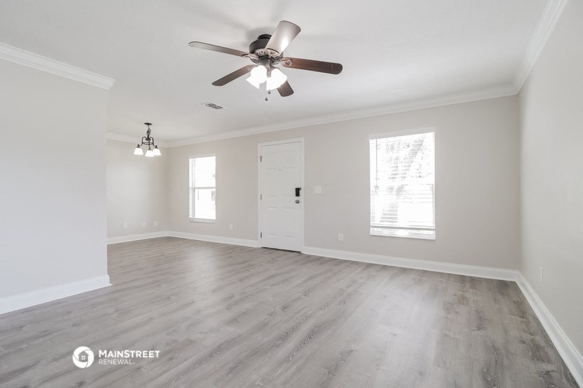 the living room of an empty house with a ceiling fan