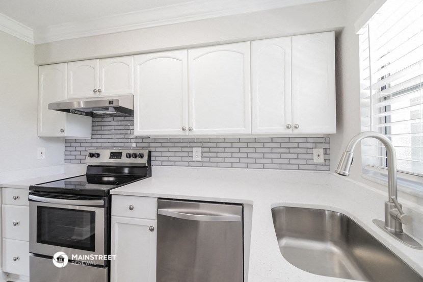 a white kitchen with white cabinets and stainless steel appliances