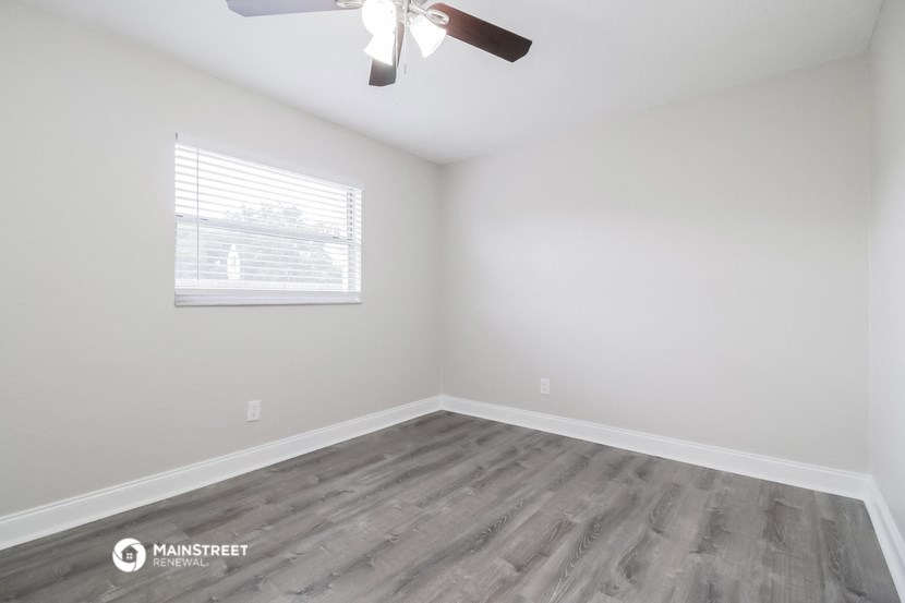 an empty room with a ceiling fan and a window
