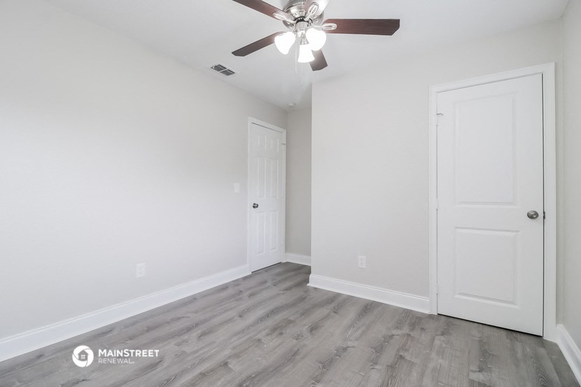 the living room of a new home with white walls and a ceiling fan