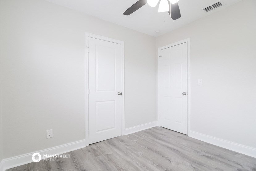 a bedroom with two doors and a ceiling fan