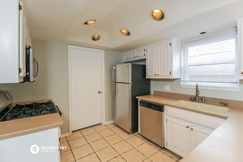 a kitchen with white cabinets and a sink and a refrigerator