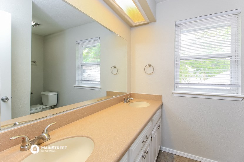the master bathroom has a large mirror and dual sinks