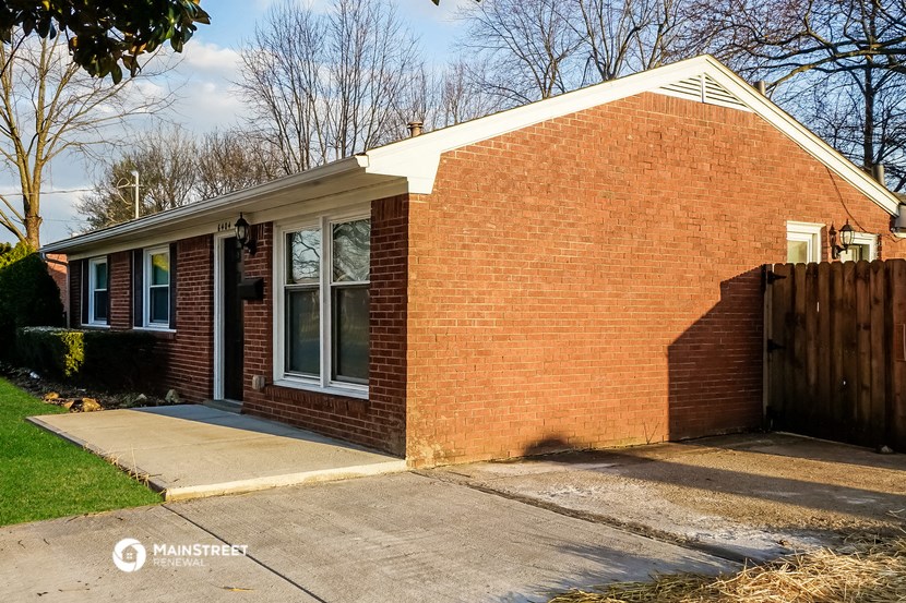 a small brick house with a sidewalk in front of it
