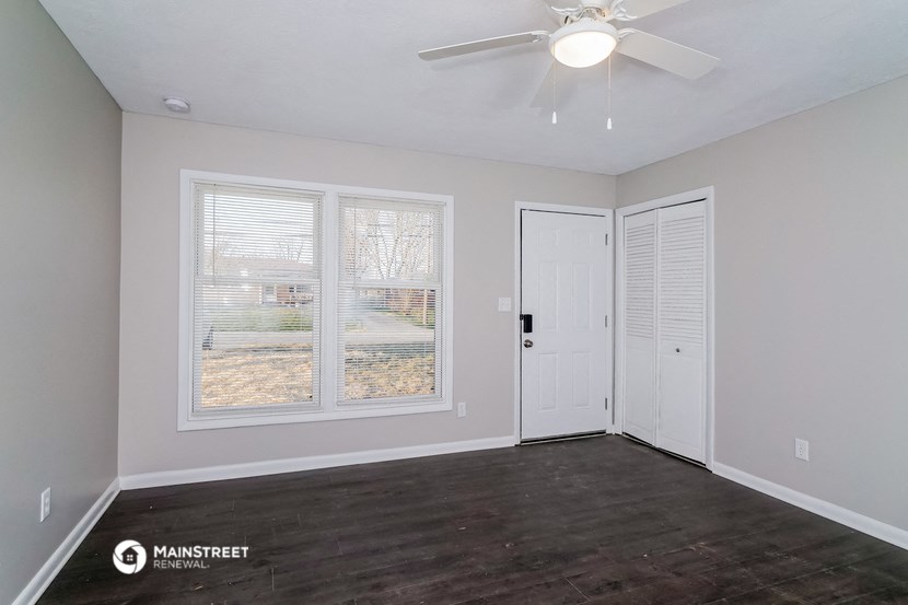 the living room of a home with a large window and a ceiling fan
