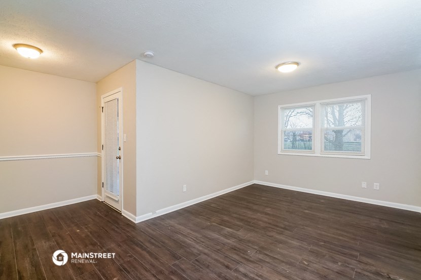 the spacious living room with wood flooring and white walls
