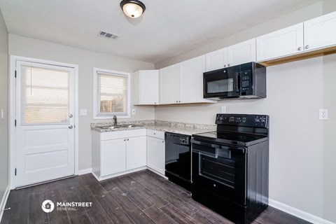 a kitchen with white cabinets and a black stove and microwave