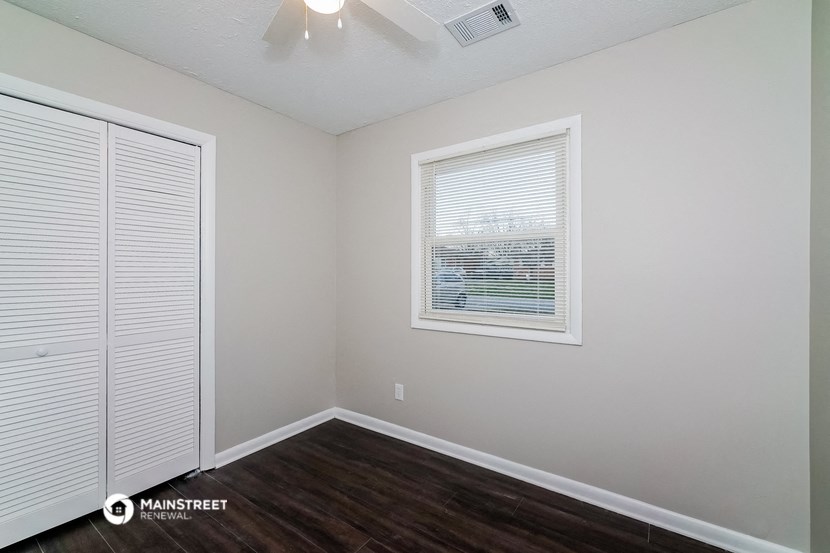 the interior of a bedroom with wood flooring and a window