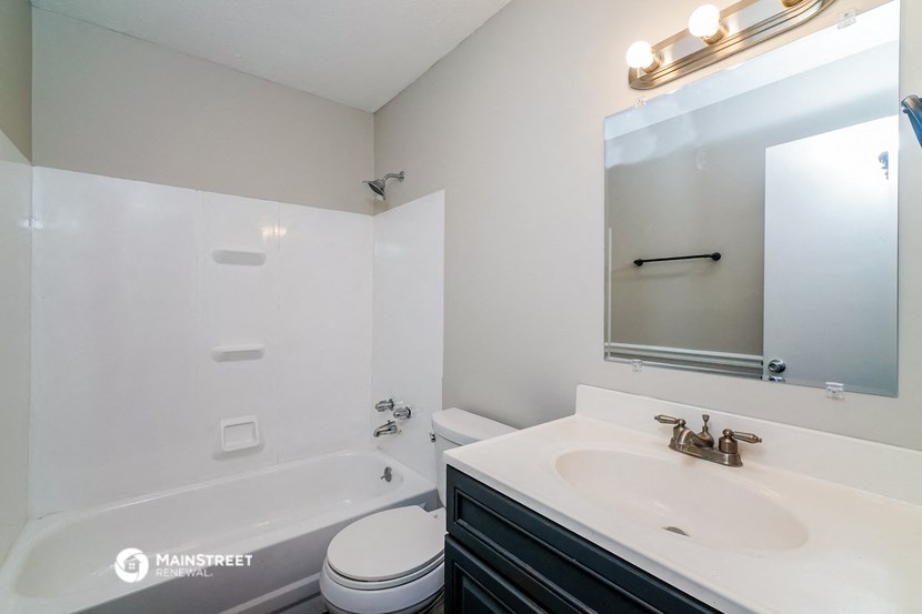 a bathroom with a sink toilet and tub and a mirror