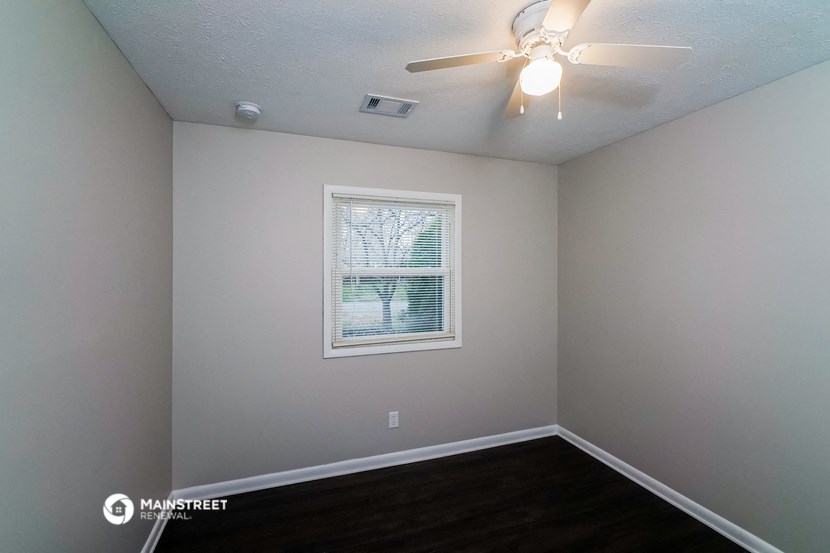 the interior of a bedroom with a window and a ceiling fan