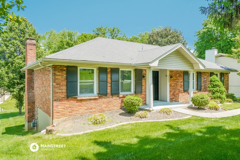a small brick house with green shutters and a lawn