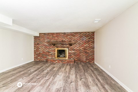 a living room with a brick fireplace and wooden floors