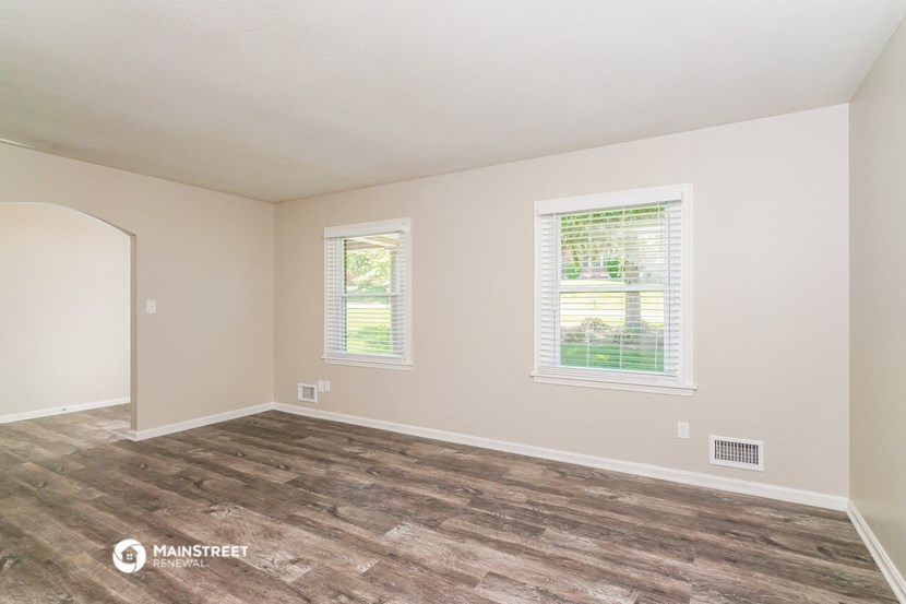 the living room of an empty home with wood flooring