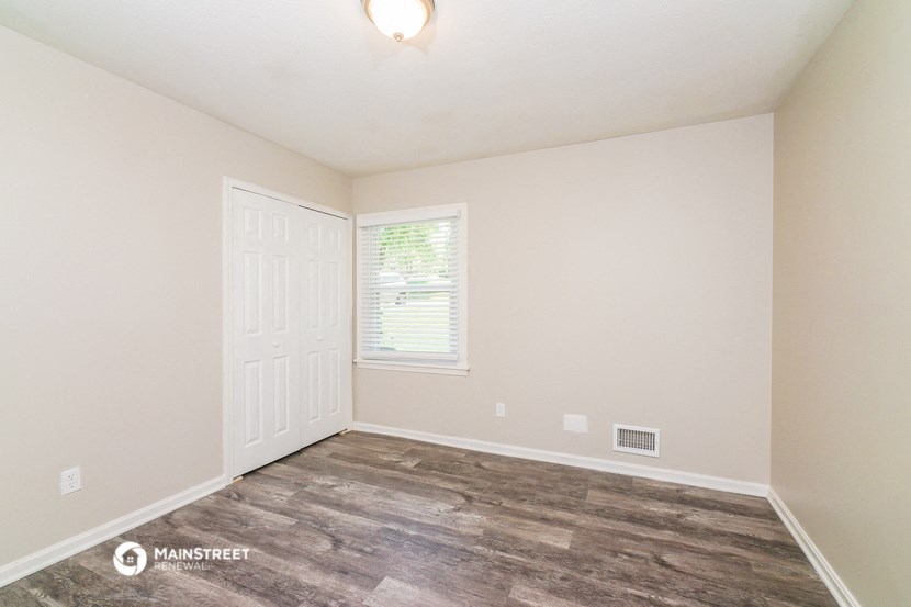 the living room of a home with a wood floor and white walls