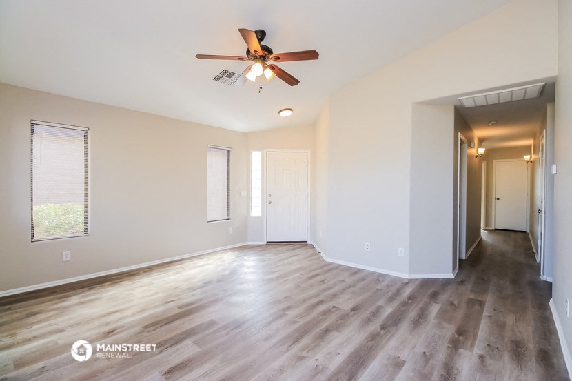 an empty living room with wood floors and a ceiling fan