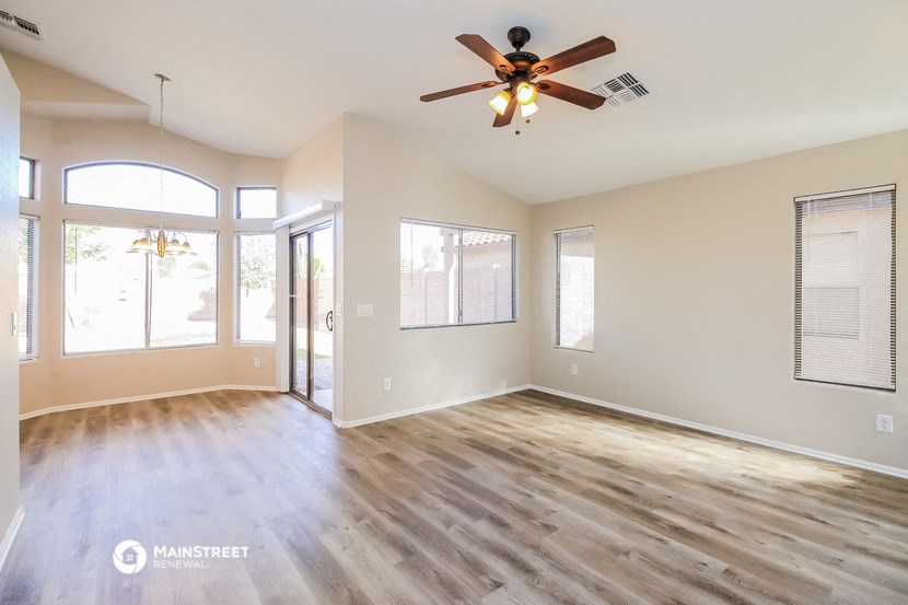 an empty living room with wood floors and a ceiling fan
