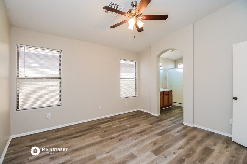 an empty living room with a ceiling fan and a bathroom
