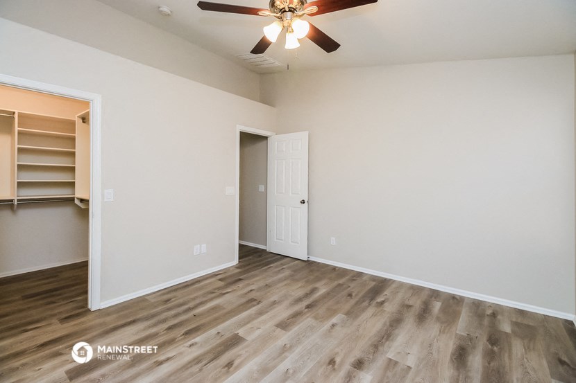 an empty living room with a ceiling fan and a closet