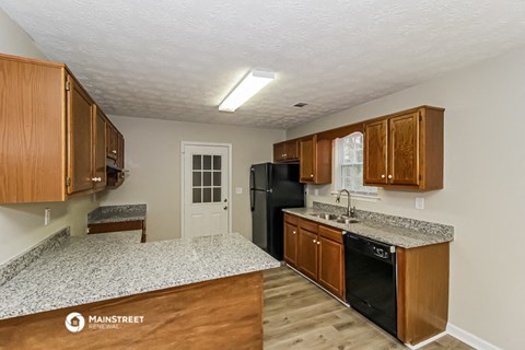 a kitchen with wooden cabinets and granite counter tops and a black refrigerator