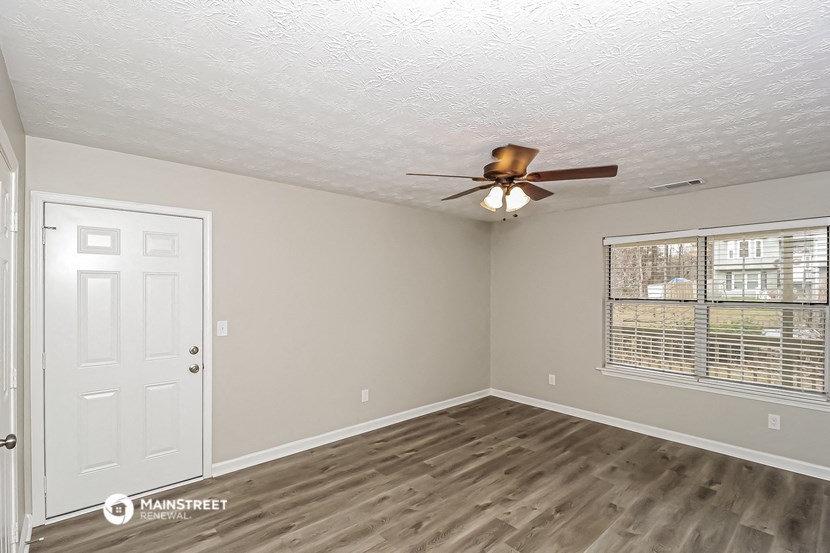 the spacious living room with a ceiling fan and a window
