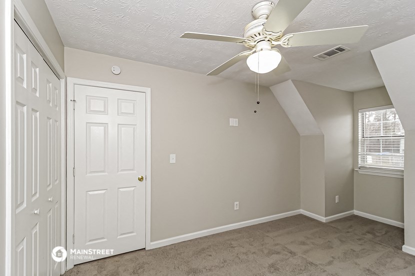 a bedroom with a ceiling fan and a closet