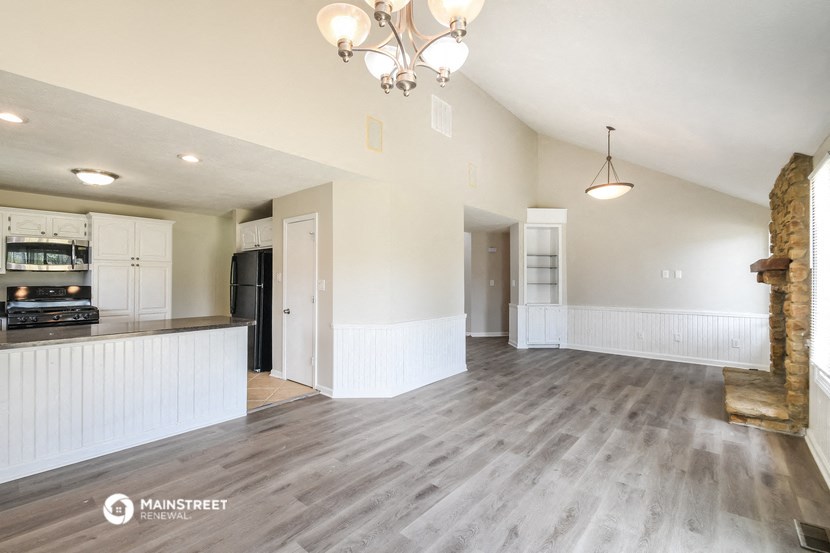 an empty living room and kitchen with wood flooring