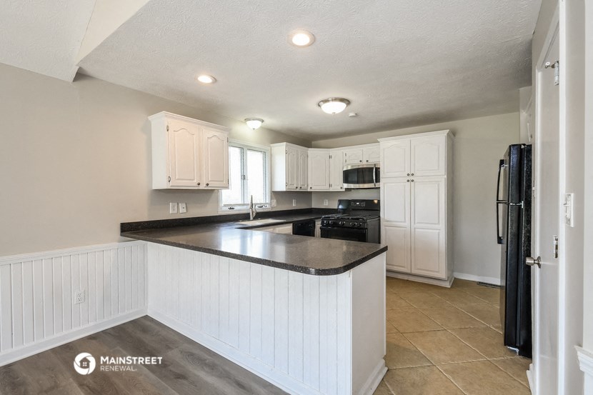 a kitchen with white cabinets and a black counter top