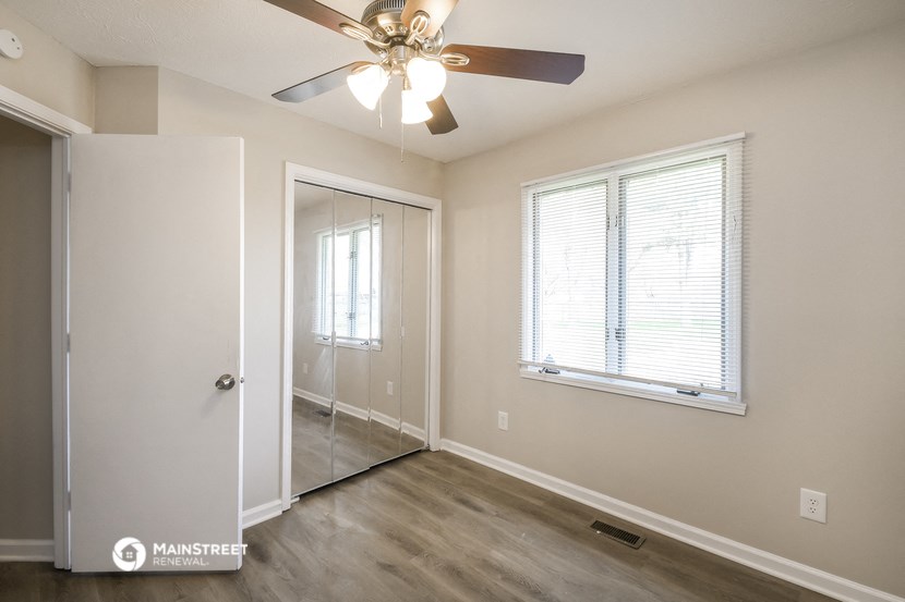 an empty bedroom with a ceiling fan and a closet