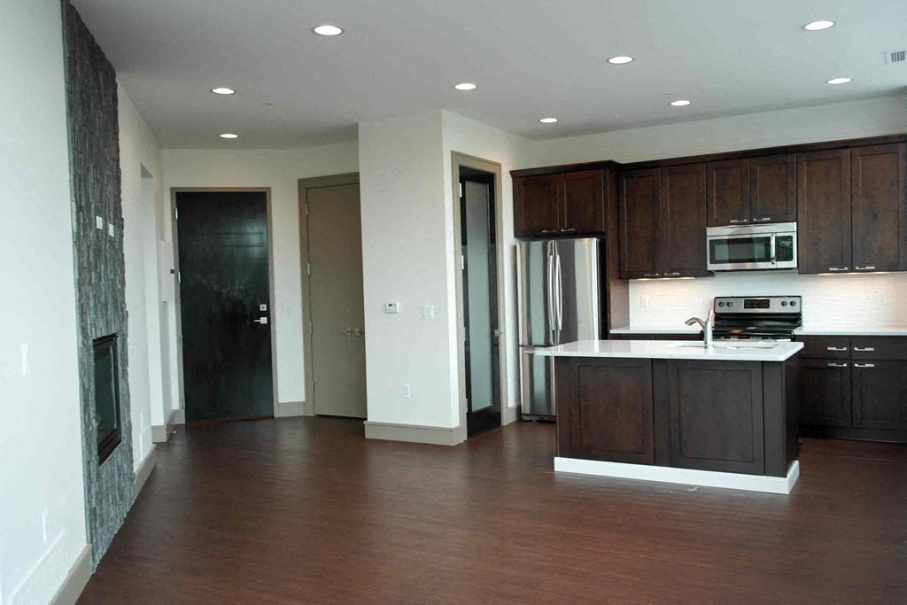 an empty kitchen with dark wood cabinets and a white counter top