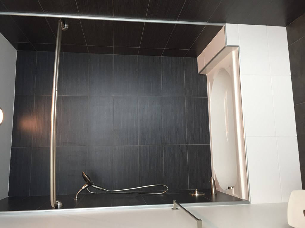 a black and white bathroom with a white tub and a black tiled wall