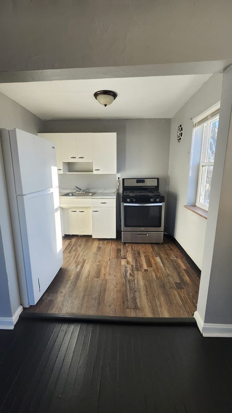 A kitchen with white cabinets and a wooden floor.