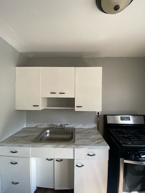A kitchen with white cabinets and a marble countertop.