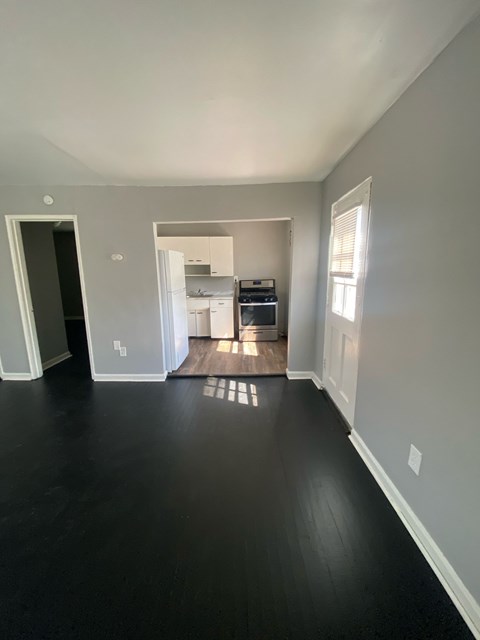 A kitchen with white cabinets and appliances is visible through an open doorway.