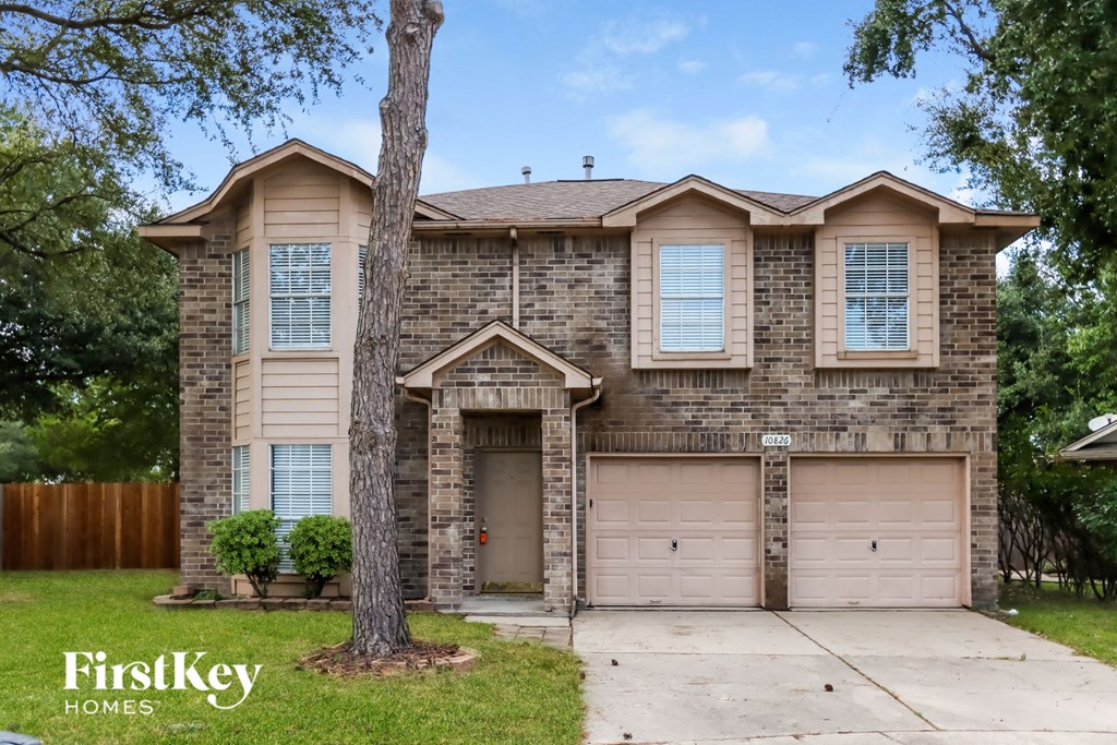 a tan brick house with two garage doors