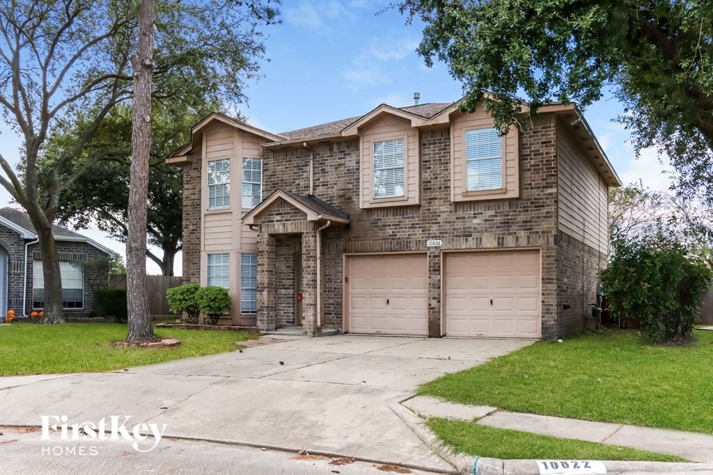 a tan brick house with two garage doors