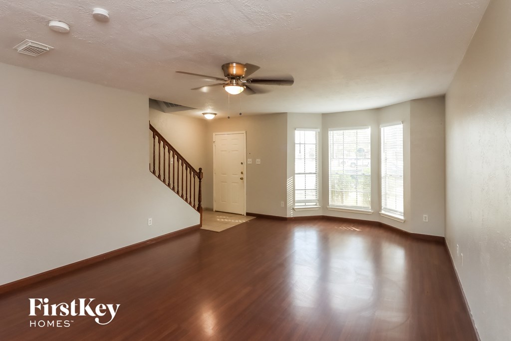 an empty living room with wood floors and a ceiling fan