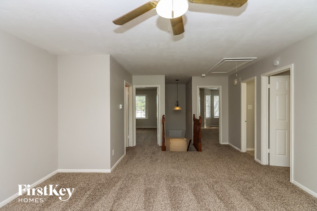 a living room with a ceiling fan and a carpeted floor