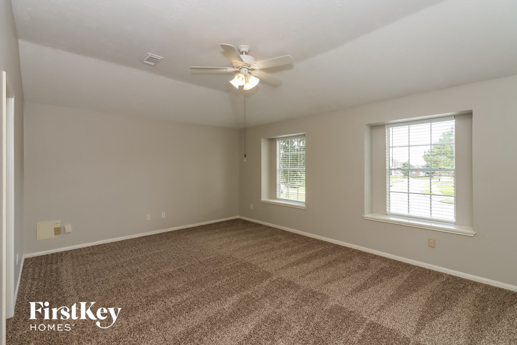 an empty living room with carpet and a ceiling fan
