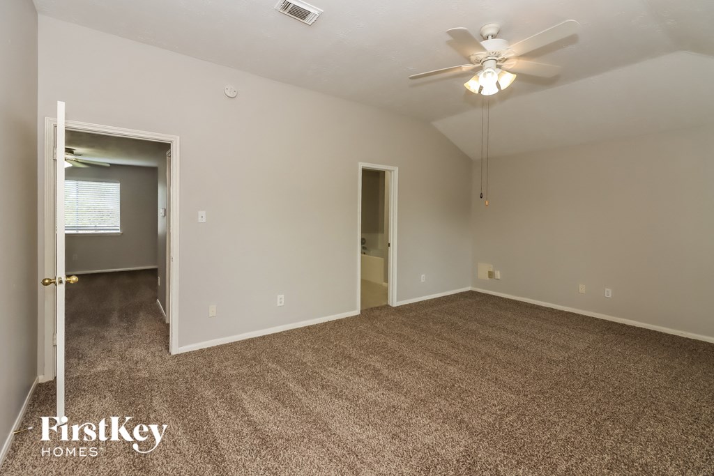an empty living room with carpet and a ceiling fan