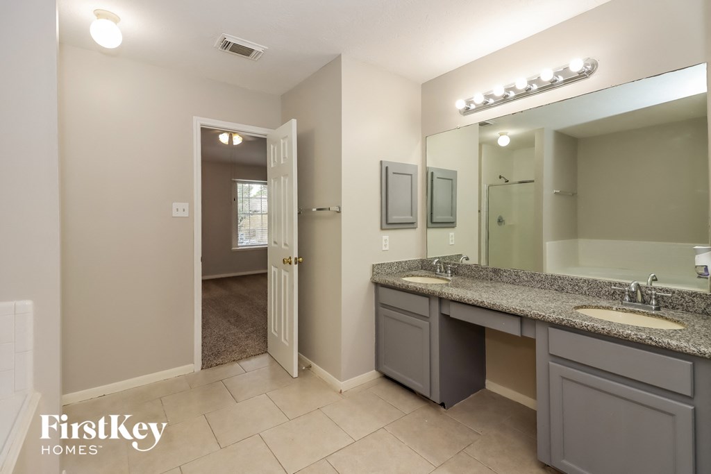 the master bathroom has dual sinks and a large mirror