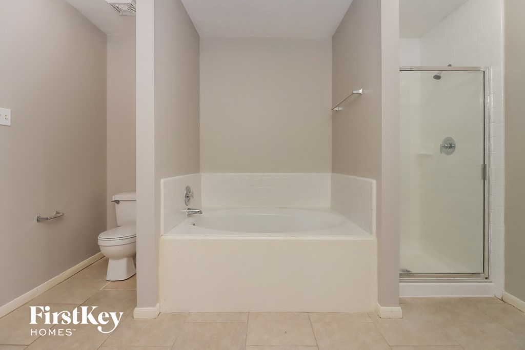 a bathroom with a tub and a shower and a toilet