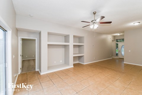 A spacious room with a ceiling fan and empty shelves.