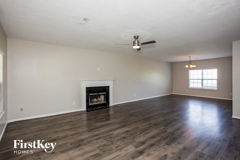 A spacious room with a fireplace and wood flooring.