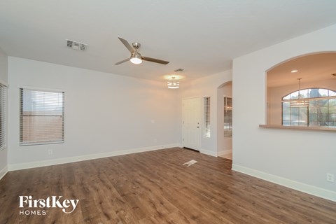 A spacious room with wooden flooring and a ceiling fan.