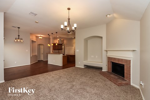 A spacious living room with a fireplace and a chandelier.