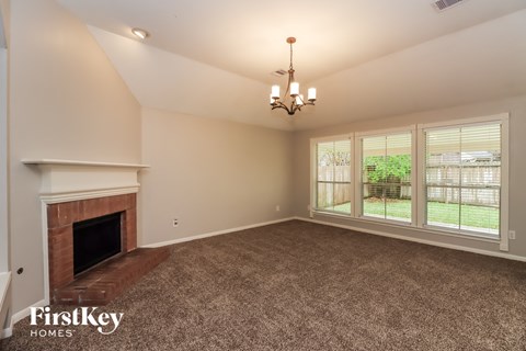 A large, empty room with a fireplace and a chandelier.