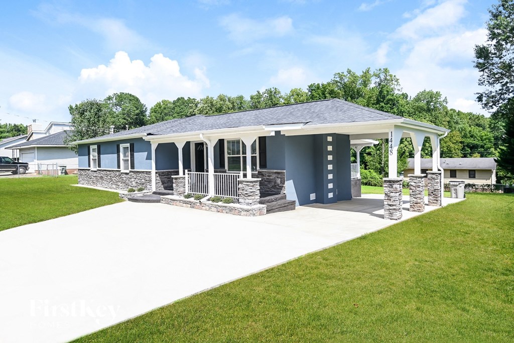 a blue house with a covered porch and a white driveway