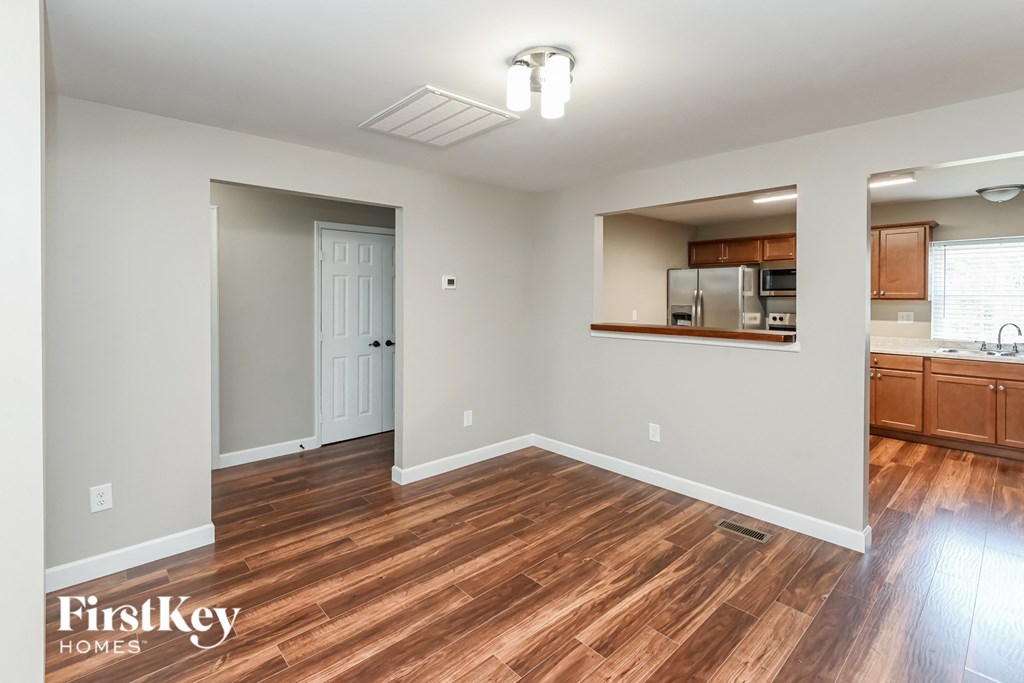 the living room and kitchen of an empty house with wood flooring